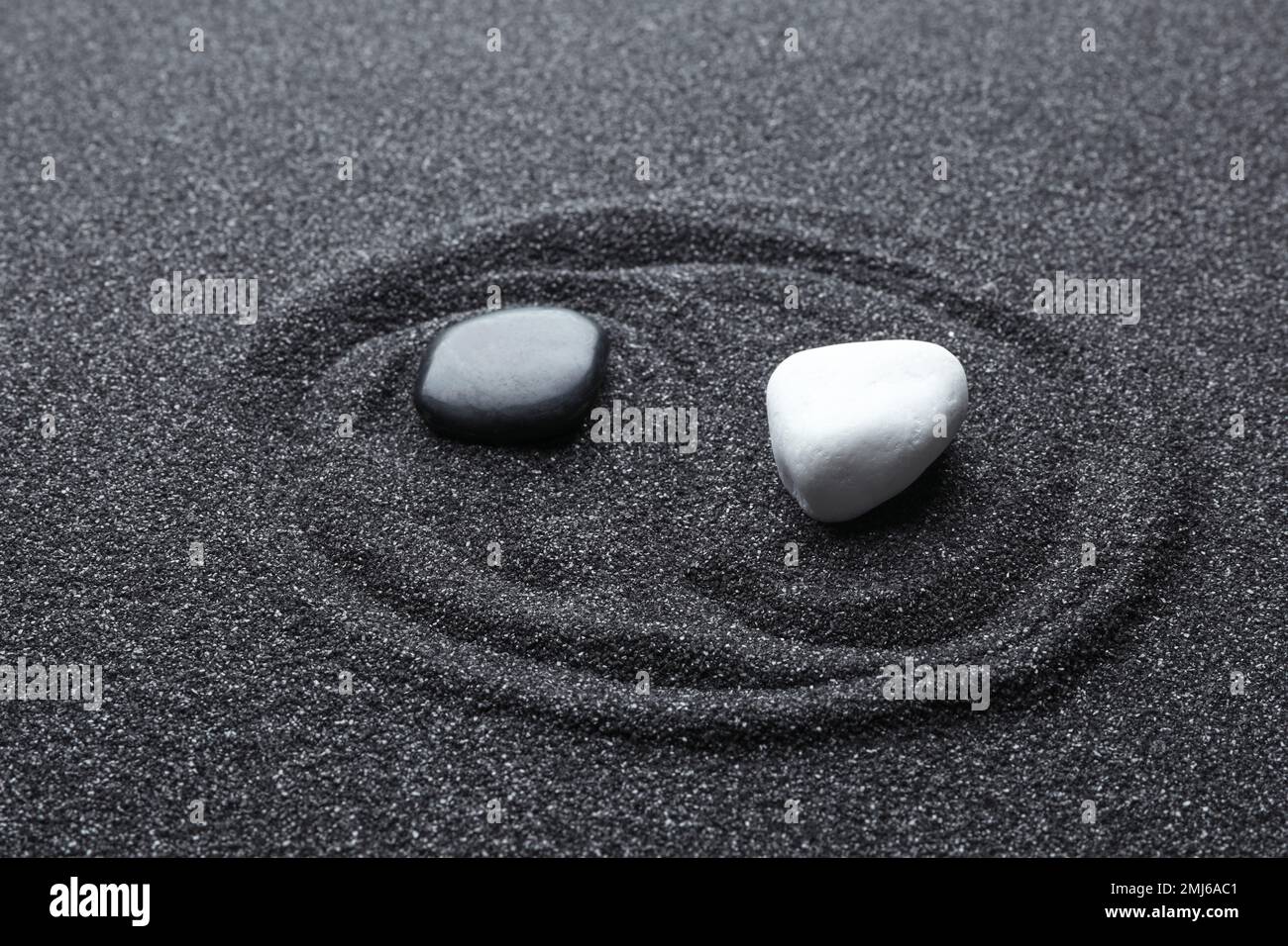 Yin Yang symbol made with stones on black sand. Zen concept Stock Photo