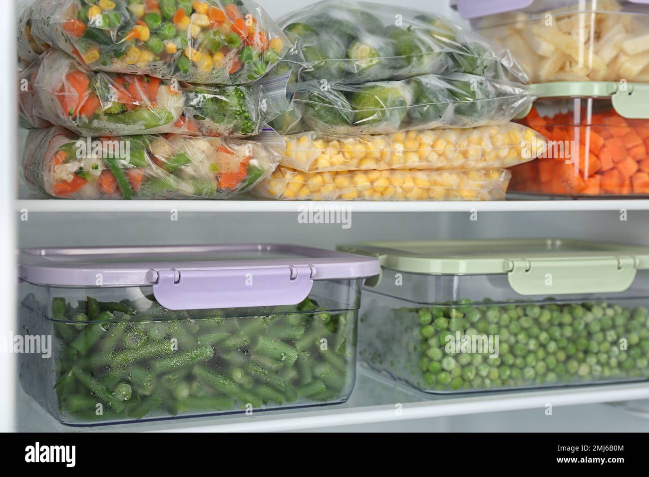 https://c8.alamy.com/comp/2MJ6B0M/plastic-bags-and-containers-with-different-frozen-vegetables-in-refrigerator-2MJ6B0M.jpg