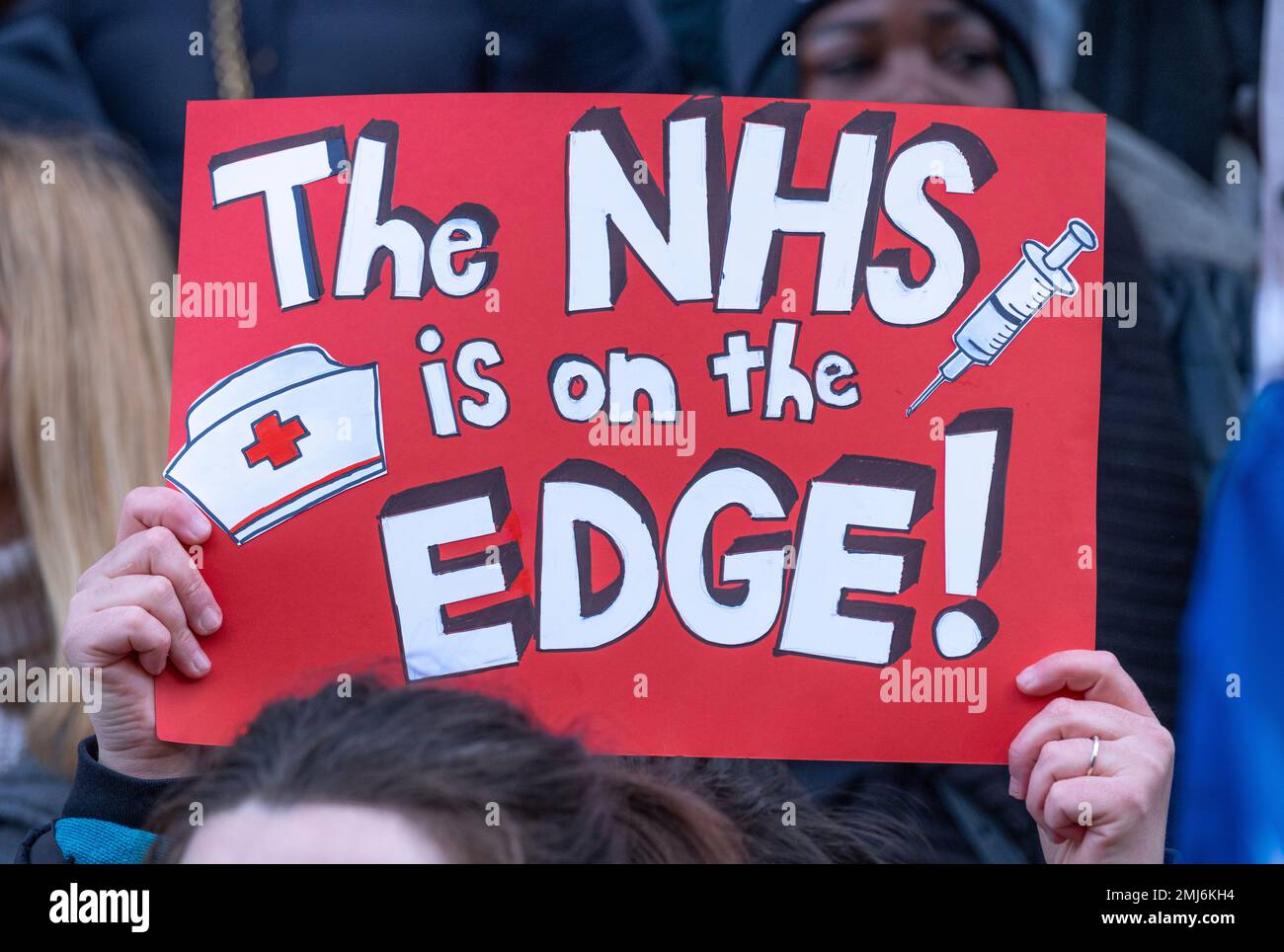 Striking nurses holding signs, demonstrating outside entrance of