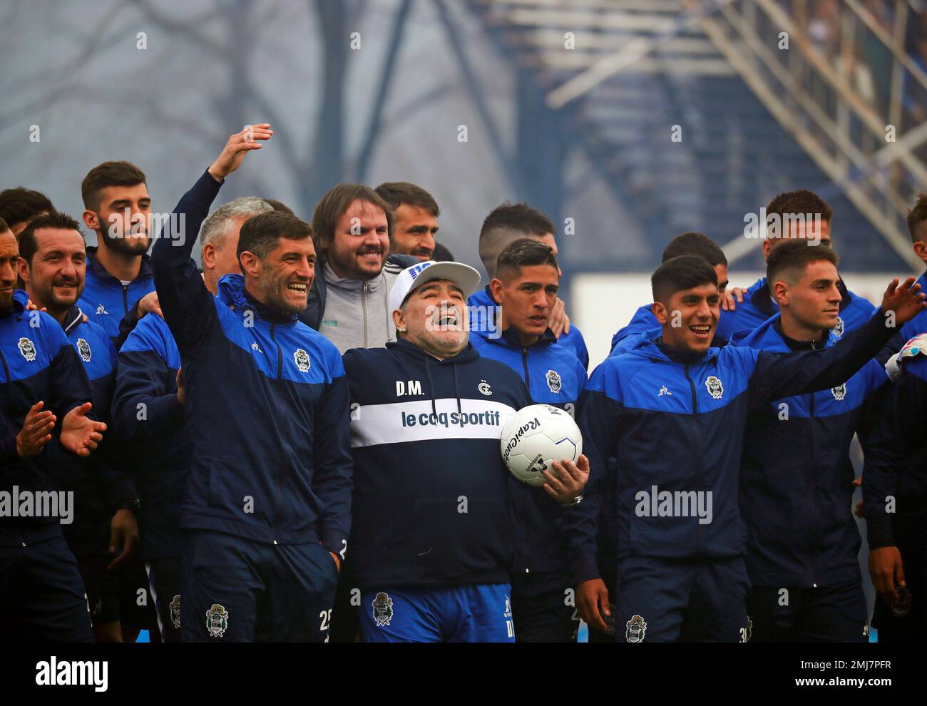 Former soccer great Diego Maradona holds a soccer ball as he walks alongside players from the soccer club Gimnasia y Esgrima La Plata during his presentation as the team s new manager in