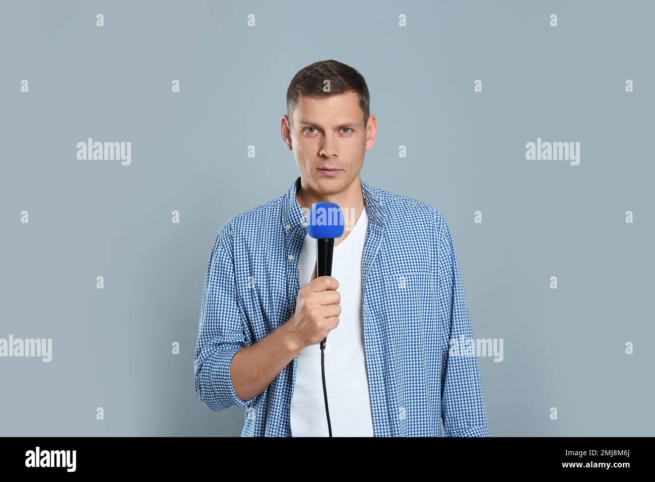 Male Journalist With Microphone On Grey Background Stock Photo Alamy