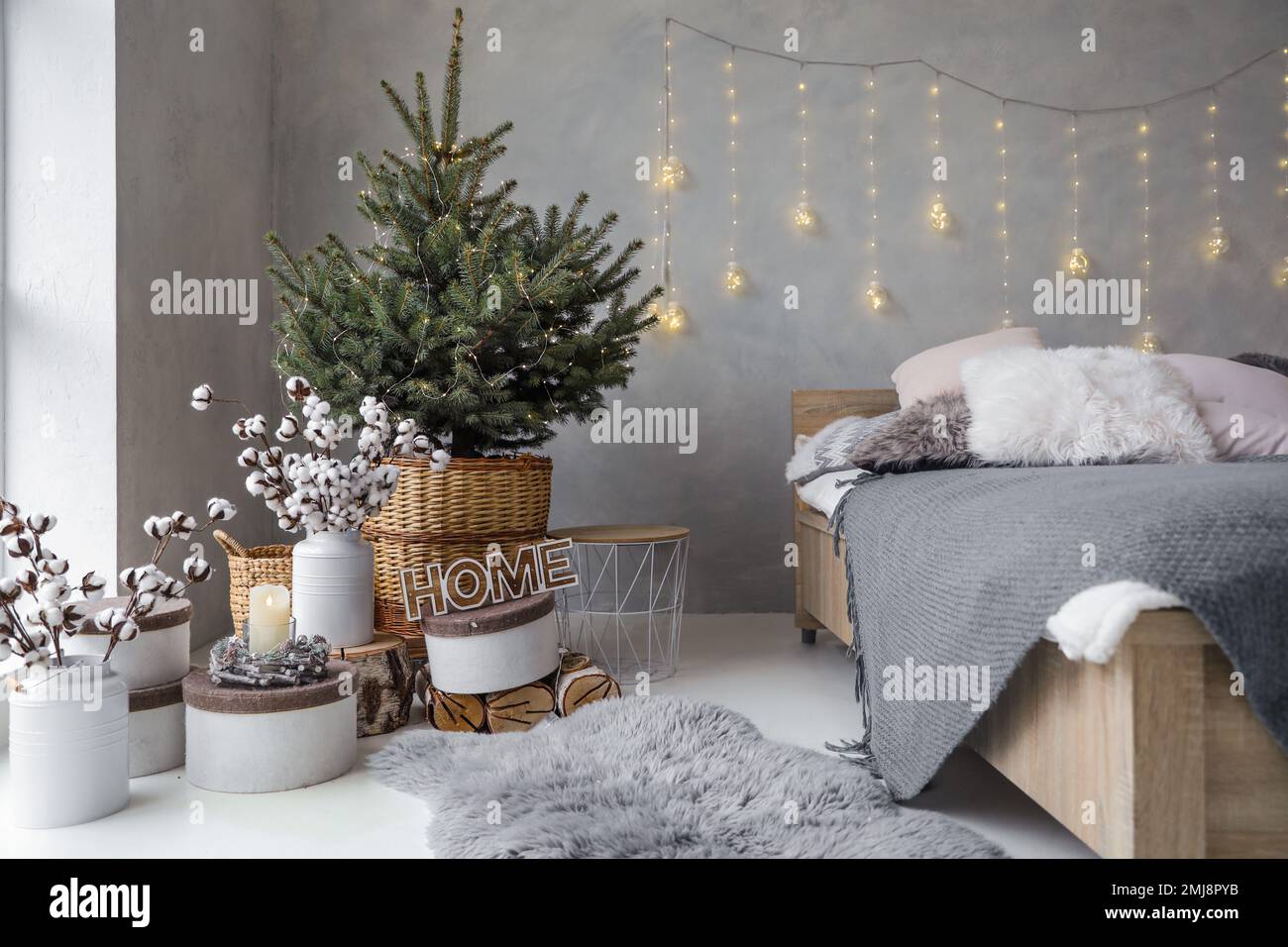 Little Christmas tree with fairy lights in bedroom interior Stock Photo