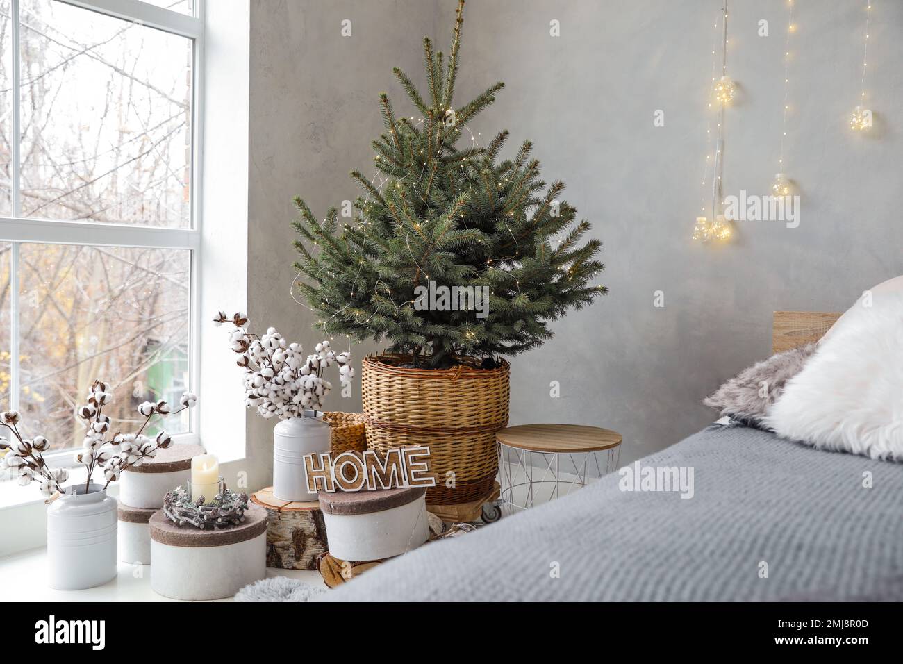 Little Christmas tree with fairy lights in bedroom interior Stock Photo