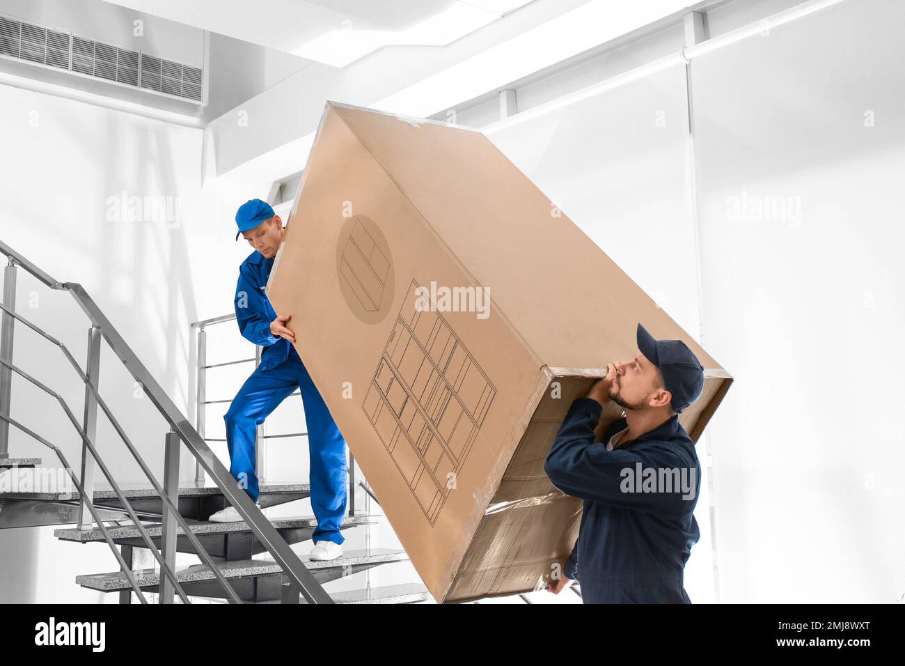 Professional workers carrying refrigerator on stairs indoors Stock