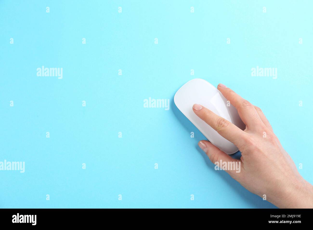 Woman using modern wireless optical mouse on light blue background, top view. Space for text Stock Photo
