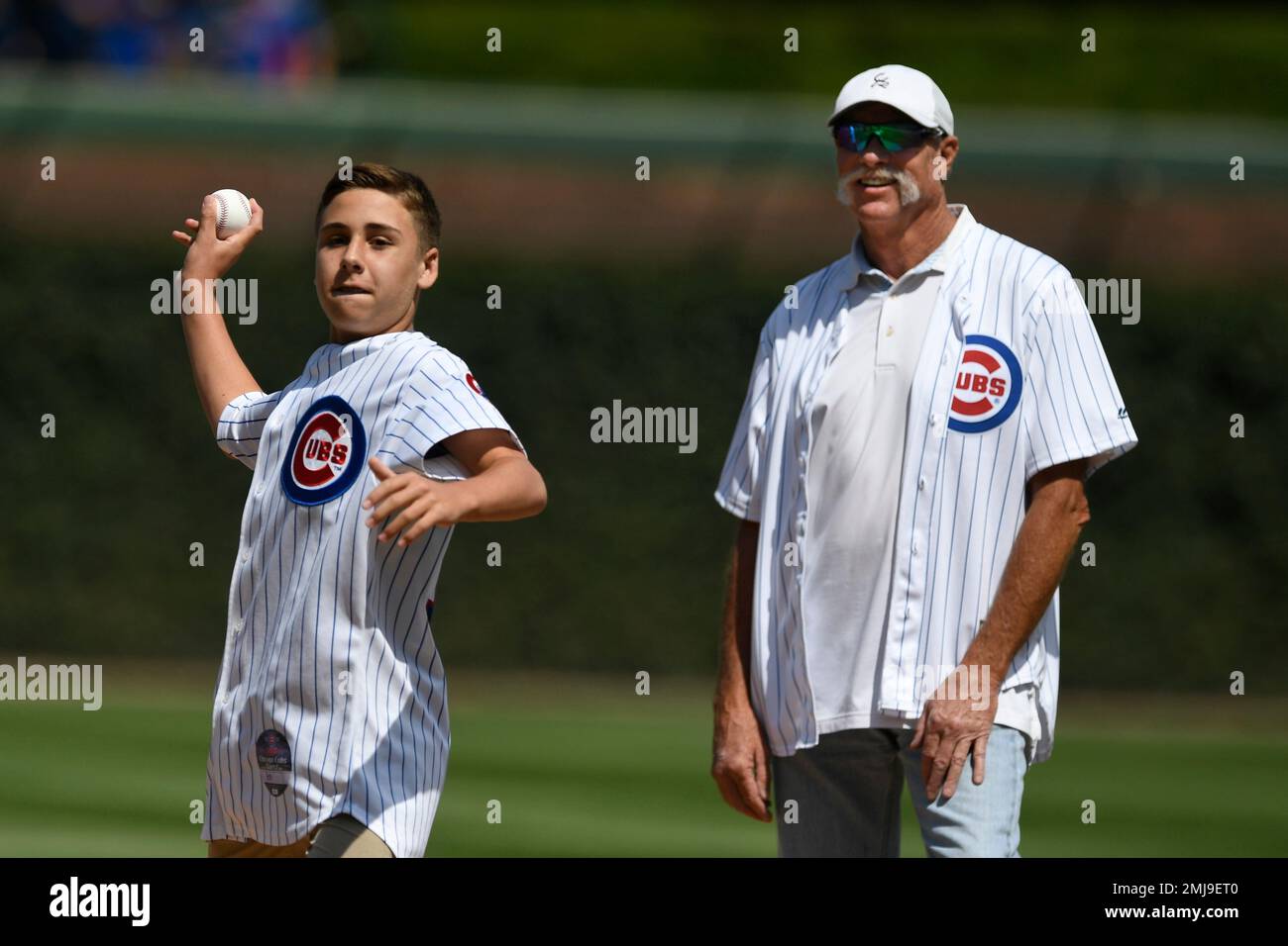 Spencer Brown, the 14 year-old grandson of the late Cubs Hall of Fame  player Ron Santo, throws out the ceremonial first pitch while Hall of Fame  pitcher Rich Goose Gossage right, looks
