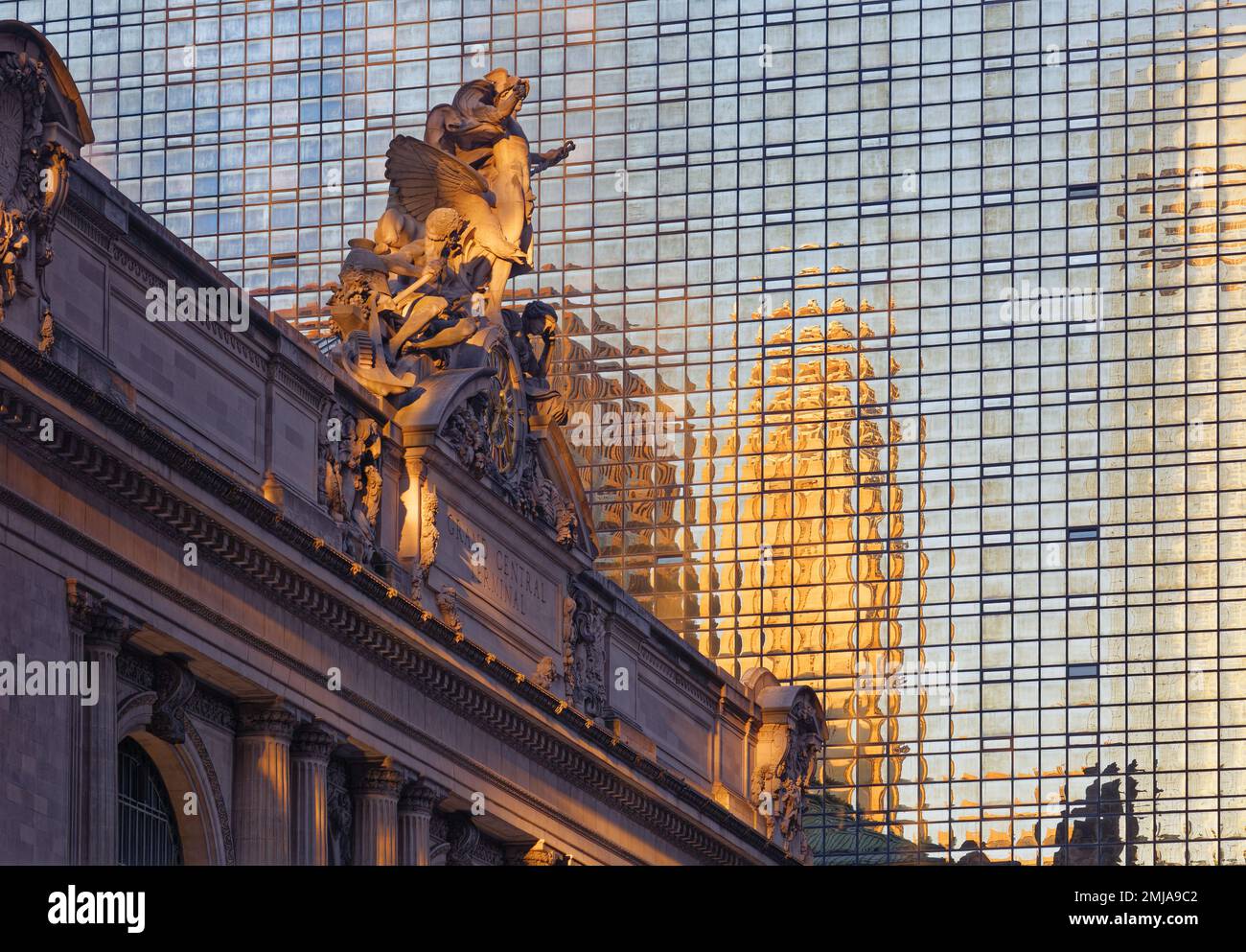 Grand Central Terminal’s iconic statues and clock above the 42nd Street entrance glow gold at dawn, against backdrop of Hyatt Grand Central New York. Stock Photo