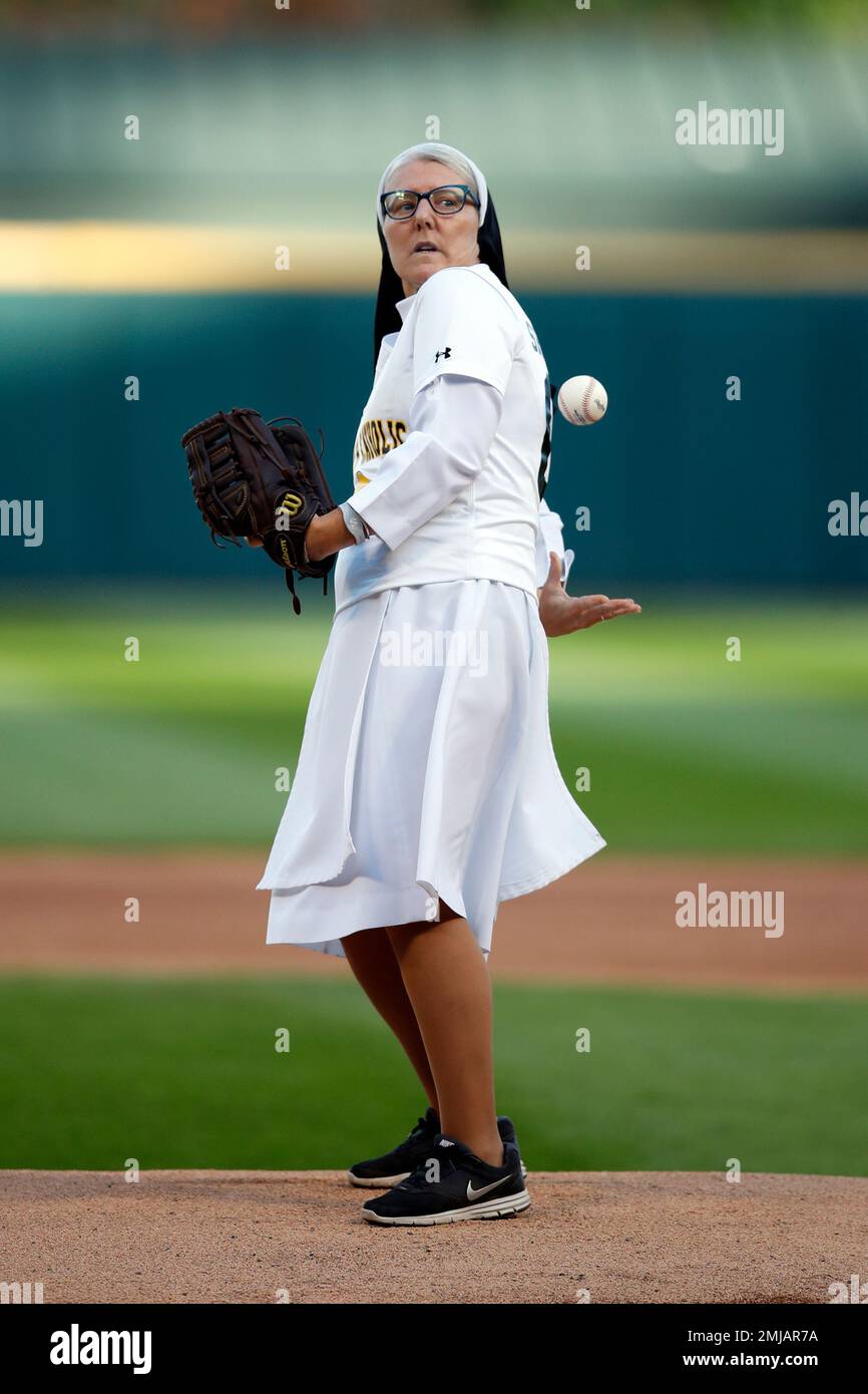 Sister Mary Jo Sobieck, a Marian Catholic High School theology teacher,  tosses the ball behind her back before throwing a ceremonial first pitch  before a baseball game between the Texas Rangers and