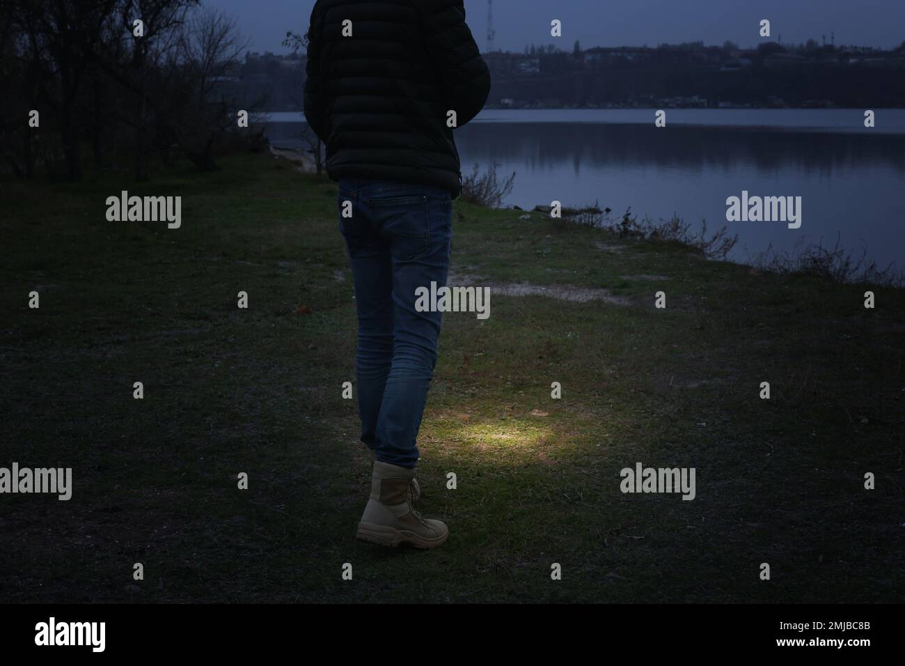 Man with flashlight walking near river, closeup Stock Photo