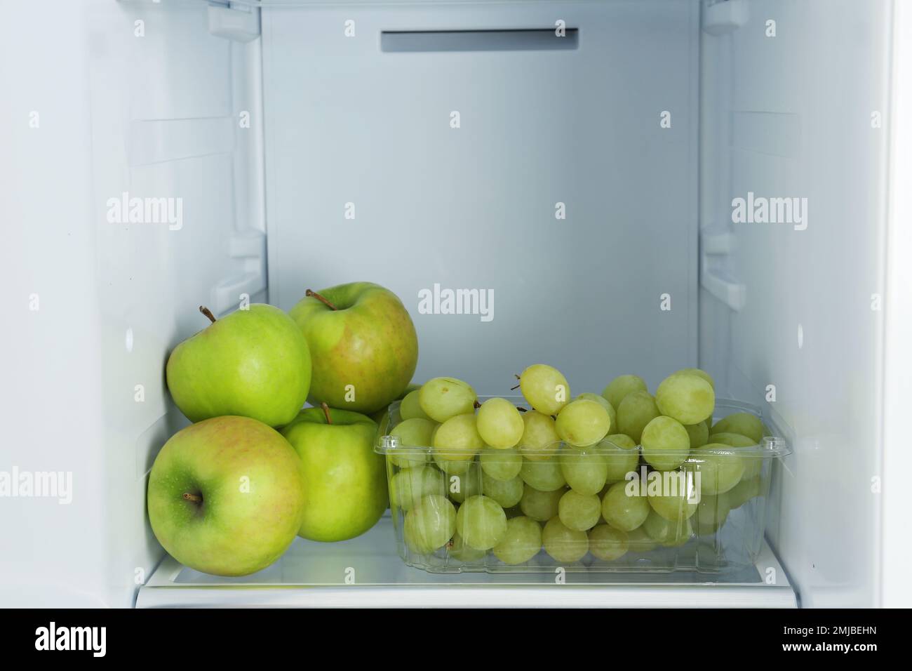 Apples and grapes on shelf in refrigerator Stock Photo Alamy