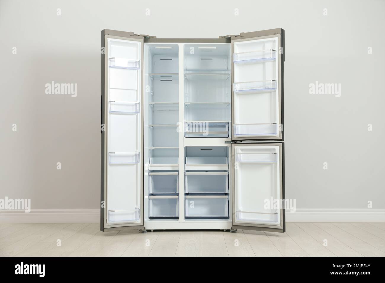 Modern empty refrigerator near light grey wall. Home appliance Stock Photo