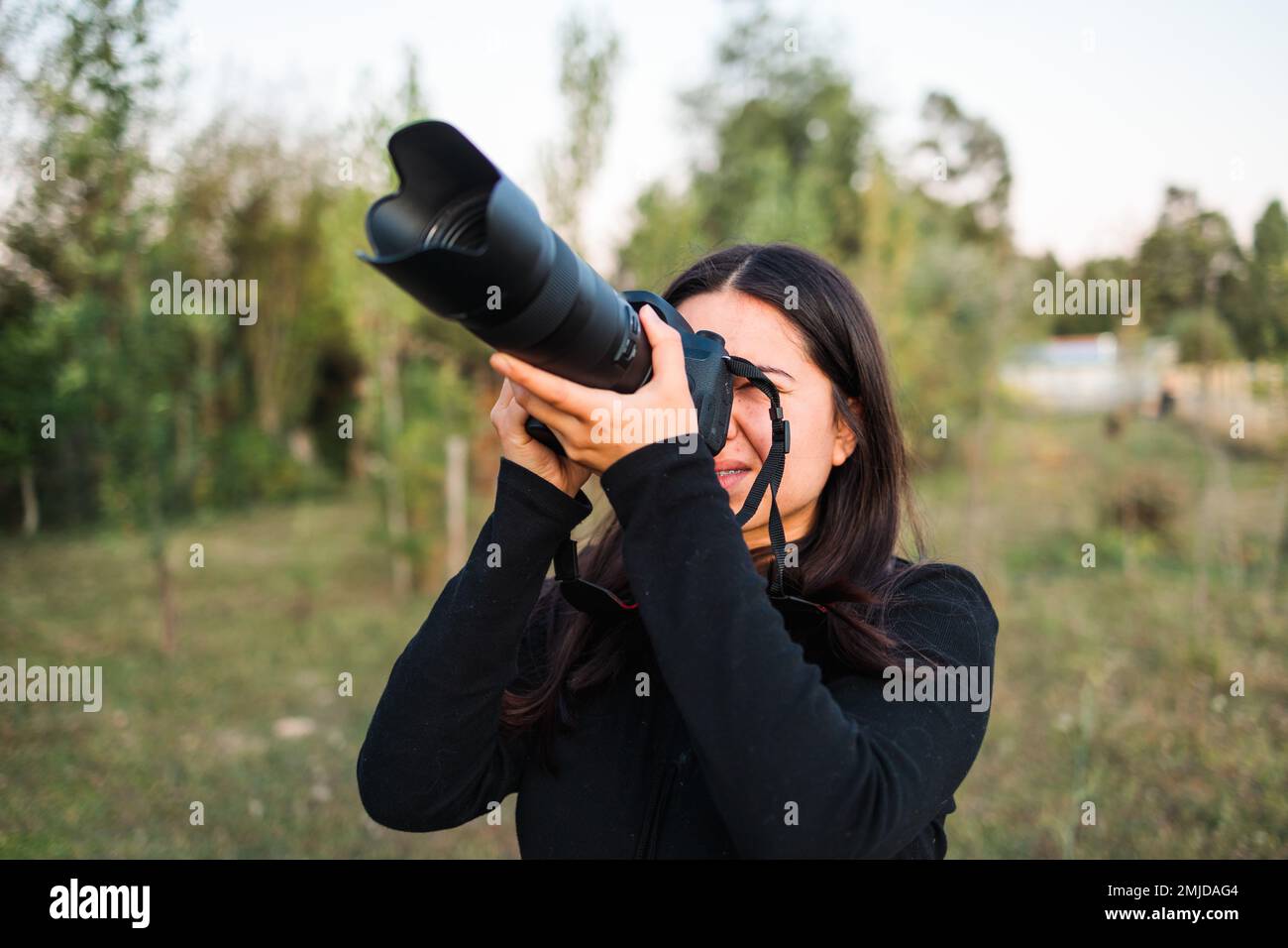 Young amateur photographer woman practicing photography to improve her mental health. Telephoto lens Stock Photo