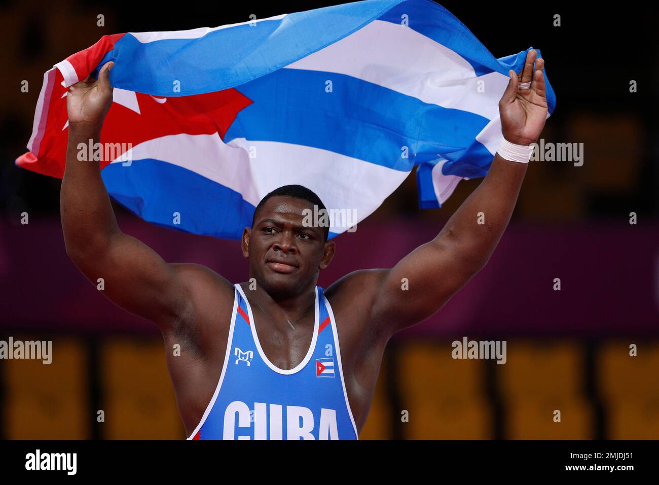 Cuba’s Mijain Lopez runs with his nation’s flag after defeating