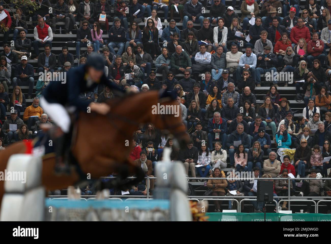 Spectators watch as Colomibas Rodrigo Diaz on his horse Alonzo D Ete takes a jump in the first classification round of individual and team equestrian jumping at the Pan American Games in