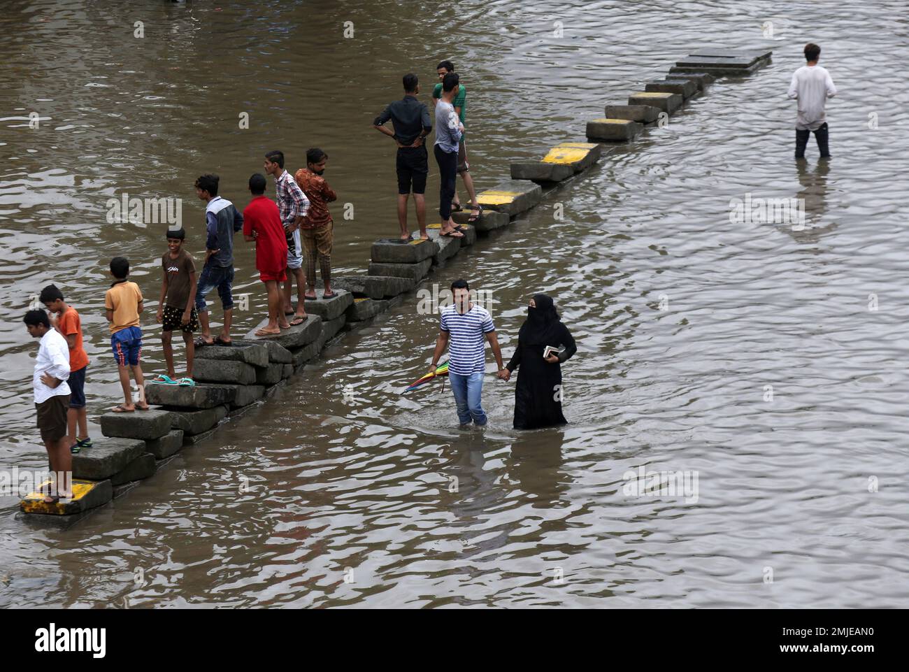 People walk through a flooded street following heavy monsoon rains in ...