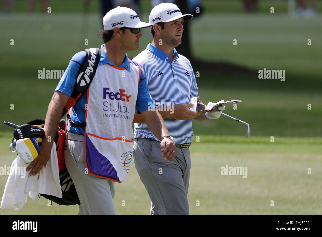 Jon Rahm, of Spain, right,walks with his caddie on the ninth hole