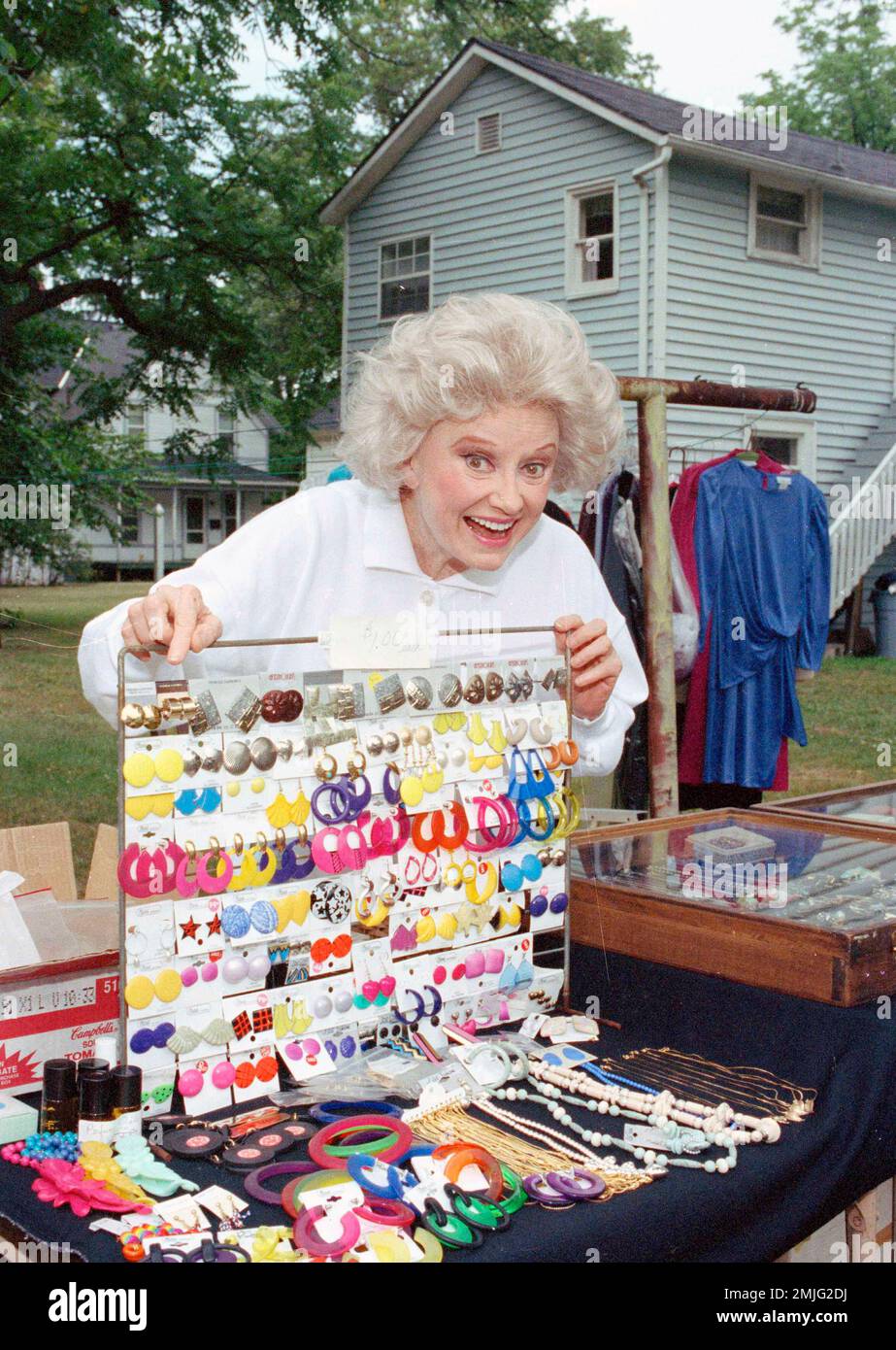 Comedian Phyllis Diller holds up dozens of pairs of earrings at a