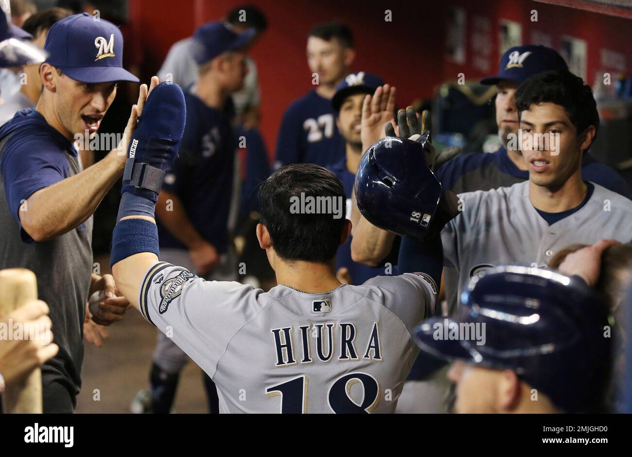 Milwaukee Brewers' Keston Hiura, center, celebrates his run scored against  the Arizona Diamondbacks with teammates Christian Yelich, right, and Brent  Suter, left, during the eighth inning of a baseball game Sunday, July