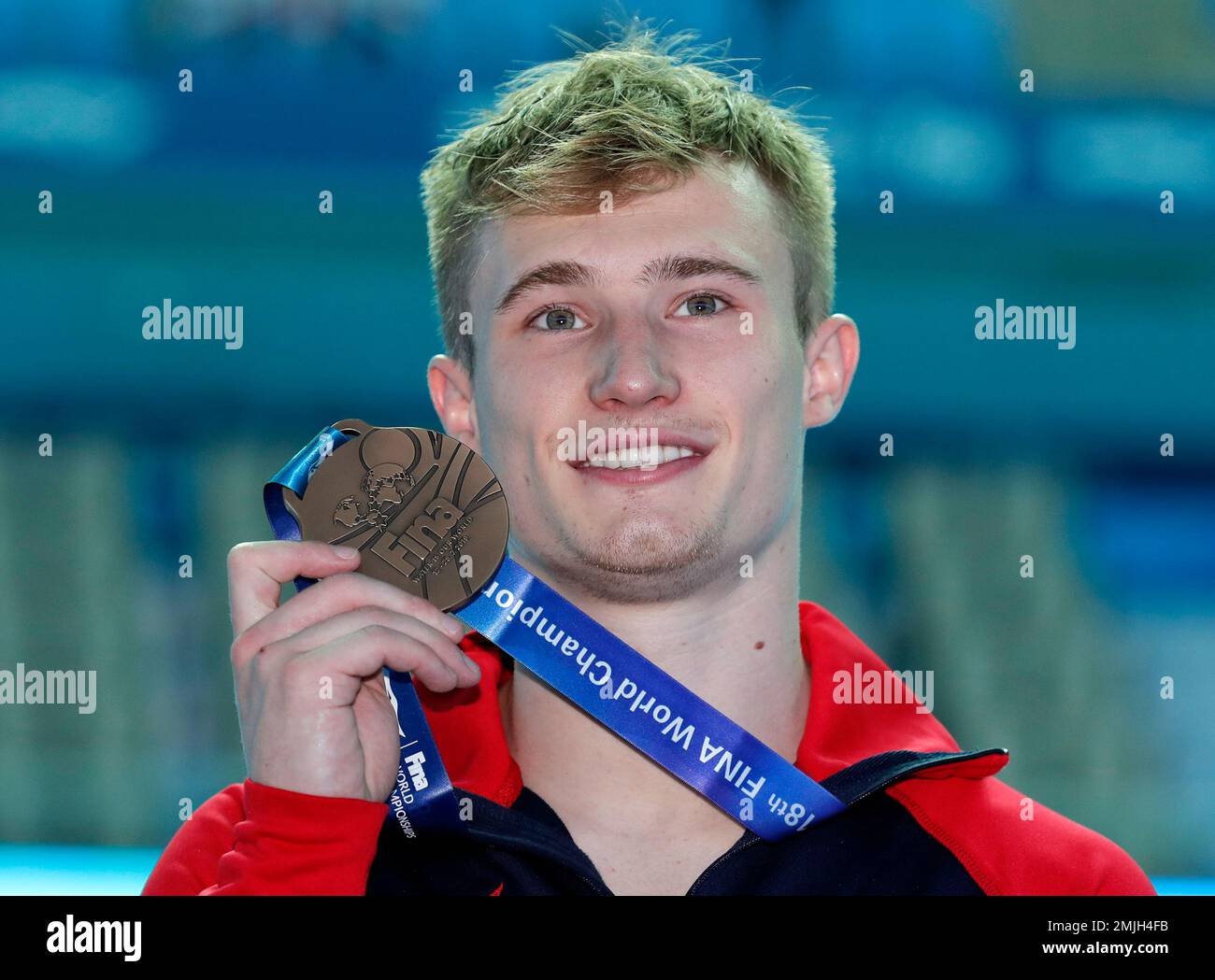 Britain's Jack Laugher holds up his bronze medal following the men's 3m