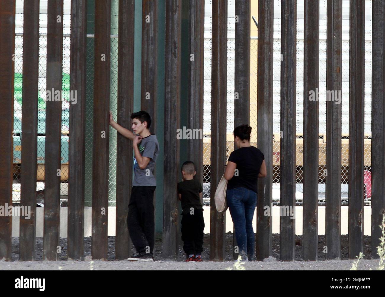 Three migrants who had managed to evade National Guard and cross the Rio  Grande onto U.S. territory wait for Border Patrol along a wall set back  from the geographical border, in El