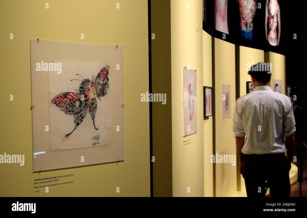 In this Wednesday, July 10, 2019 photo, a man walks near artwork created by Ed  Hardy during a media preview of "Ed Hardy: Deeper than Skin" at the de  Young Museum in