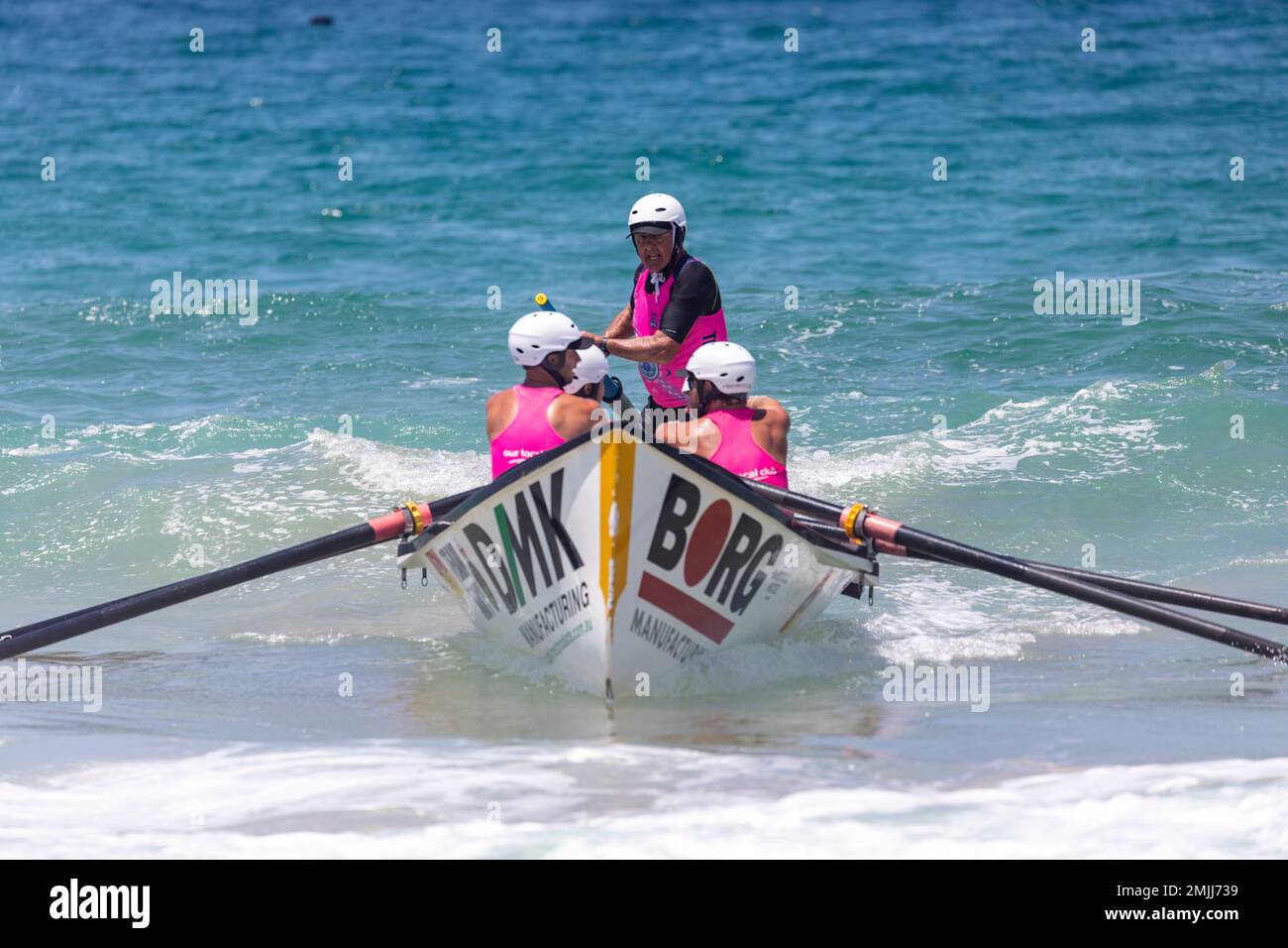Womens surfboat racing carnival at North Narrabeen beach in Sydney, traditional surfboat from local surf life saving clubs compete,NSW,Australia Stock Photo