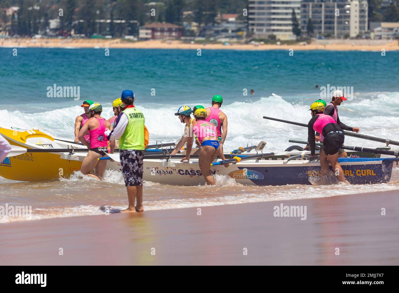 Australian 2023 surfboat racing carnival at Narrabeen beach, male and female teams, race marshal prepares for start of heat,Sydney,NSW,Australia Stock Photo