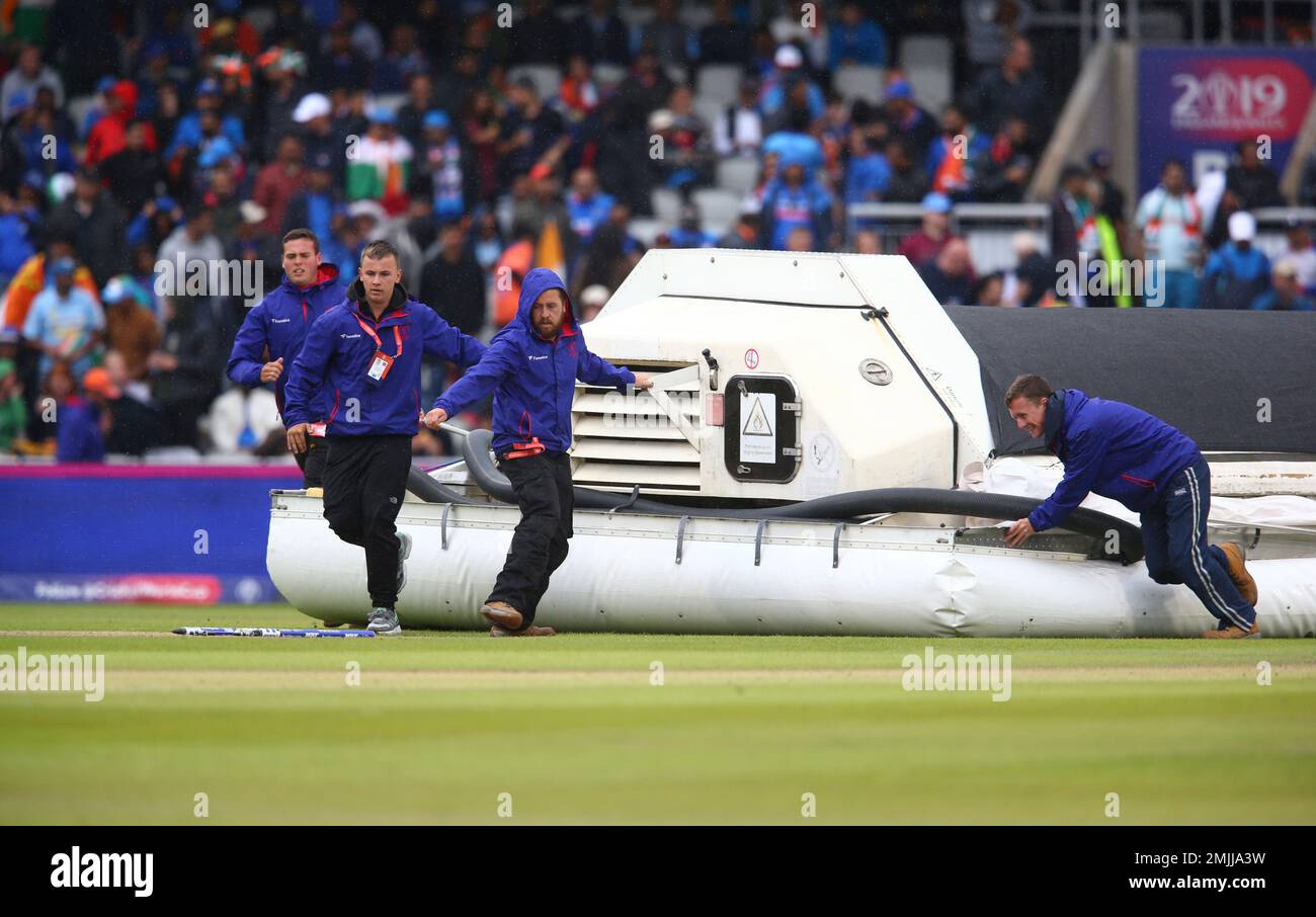 Groundsmen bring out a water removal machine as it rains during the