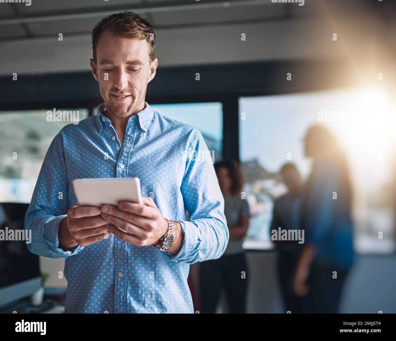Focused on the task. a handsome young designer using his digital tablet in the office. Stock Photo