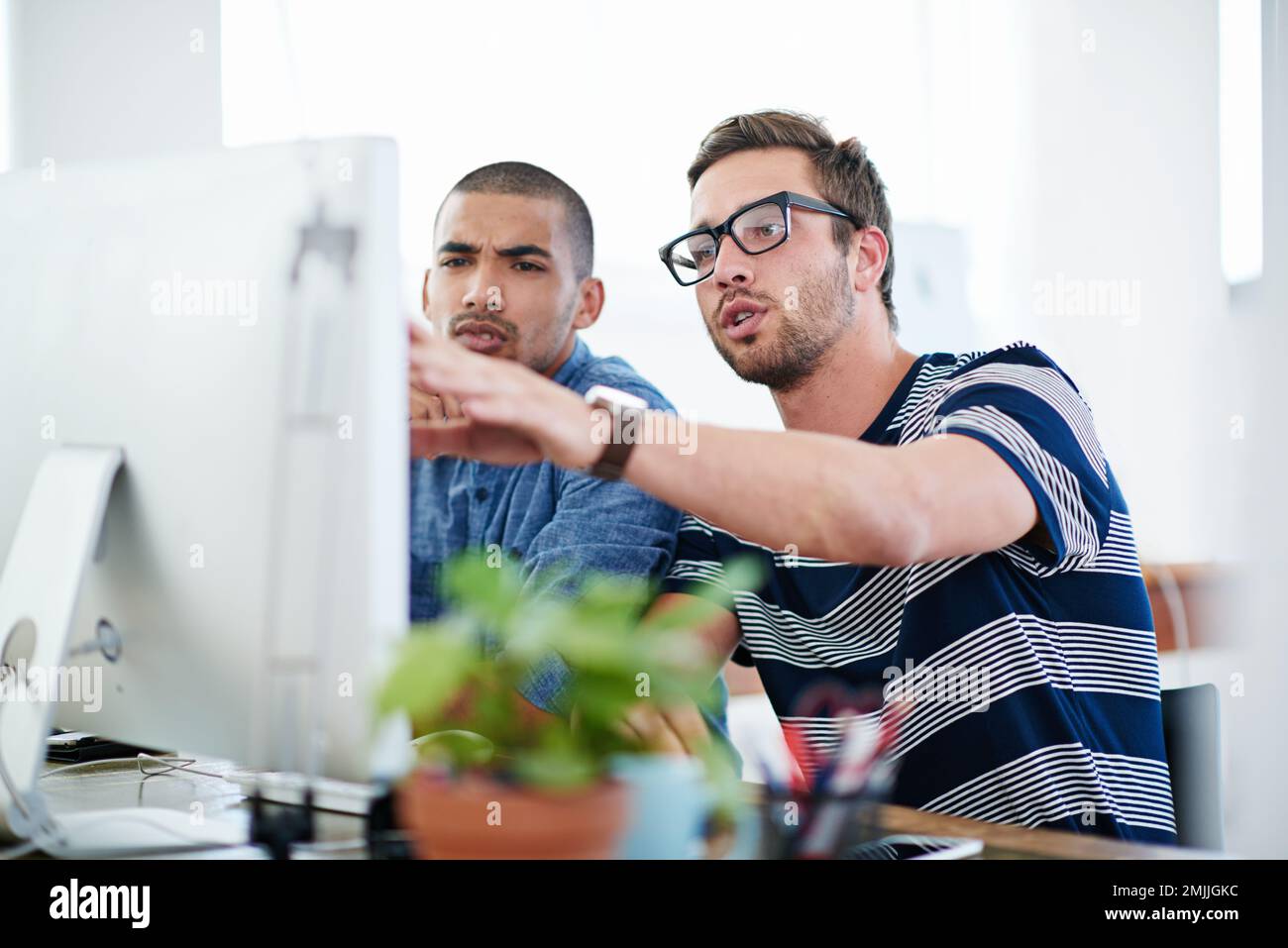 We need to find a solution for this. two male designers working together at a computer. Stock Photo