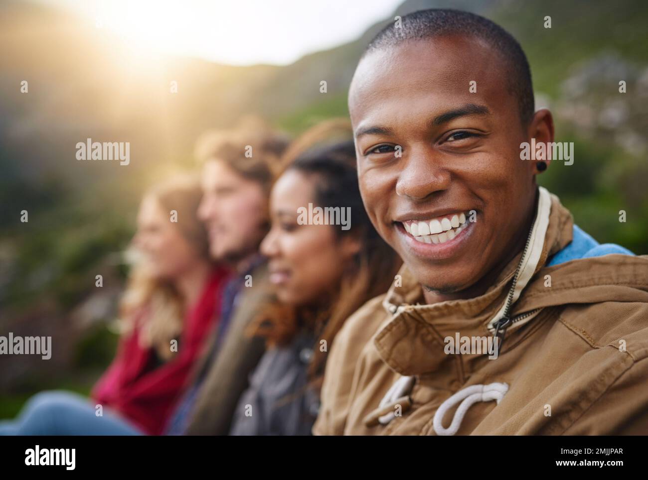 Keep your friends close. Portrait of a happy young man hanging out with his friends outside. Stock Photo