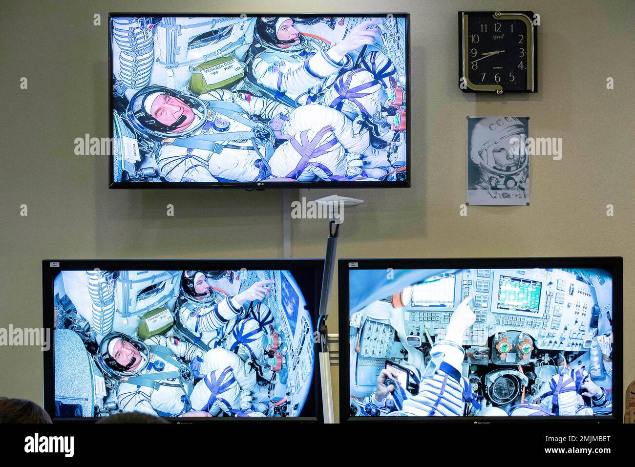 A portrait of the first man in space, Yuri Gagarin, right, is placed next  to TV screens as broadcast shows U.S. astronaut Andrew Morgan, top, and  Russian cosmonaut Alexander Skvortsov, left, attend