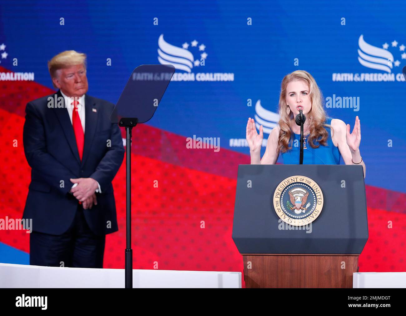 President Donald Trump, left, listens Natalie Harp, right, speak after