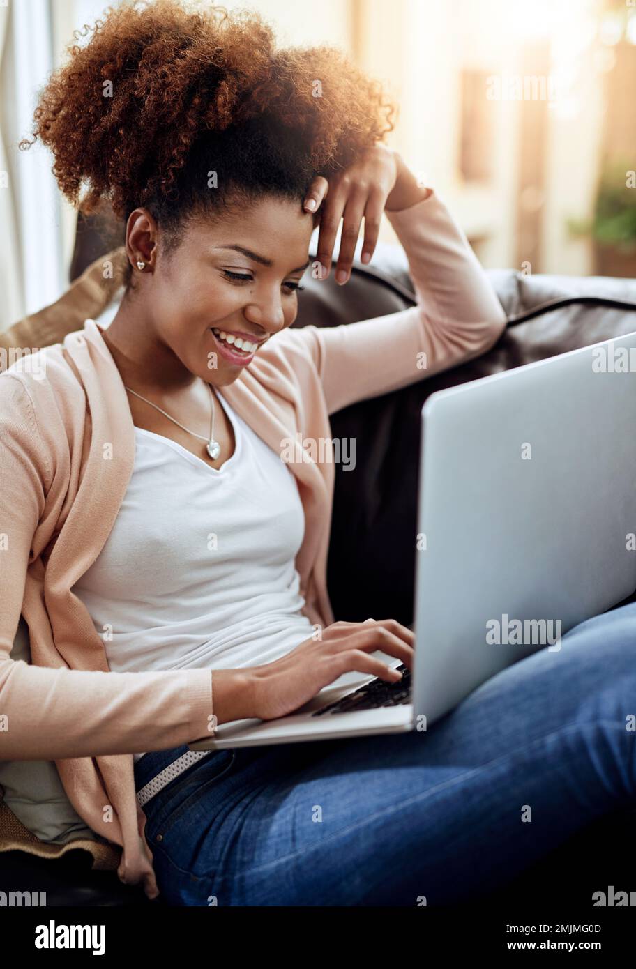 Comfy, connected and contented. a relaxed young woman using a laptop on the sofa at home. Stock Photo