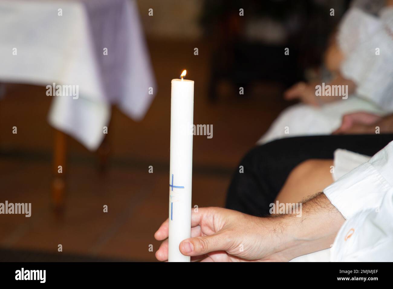 burning candle in man father hands during Baptism infant ceremony in Church Stock Photo