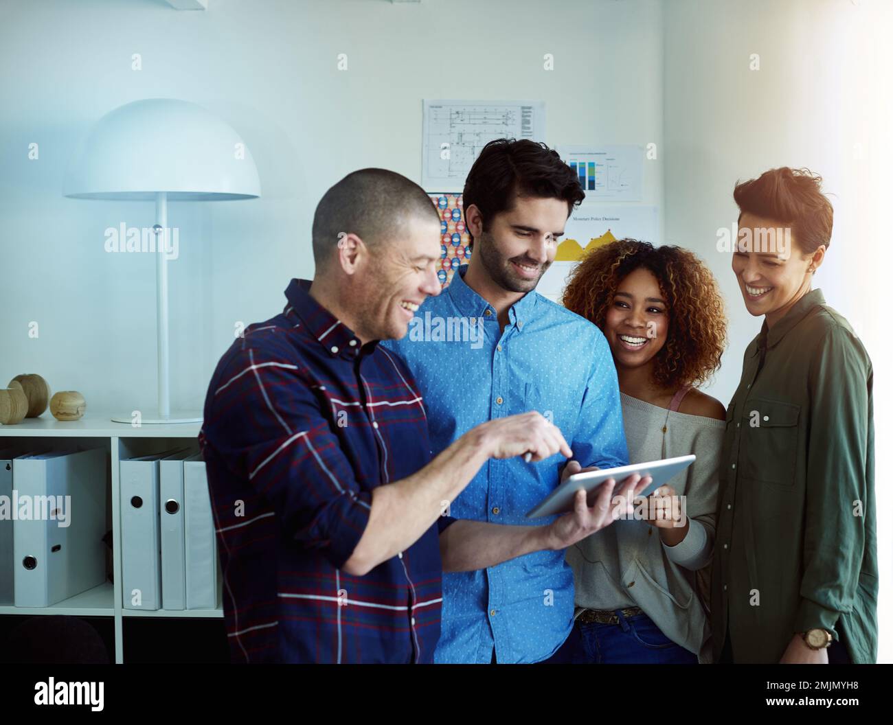 Teamwork has given us a one-stop solution. a group of coworkers discussing something on a tablet. Stock Photo