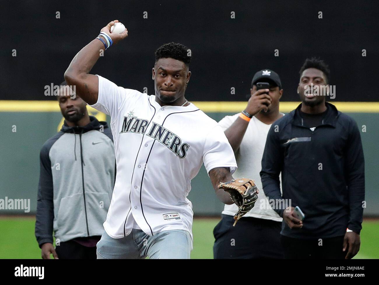 Seattle Seahawks rookie wide receiver DK Metcalf throws out the first pitch  at a baseball game between the Seattle Mariners and the Baltimore Orioles,  as other rookies from the NFL football team