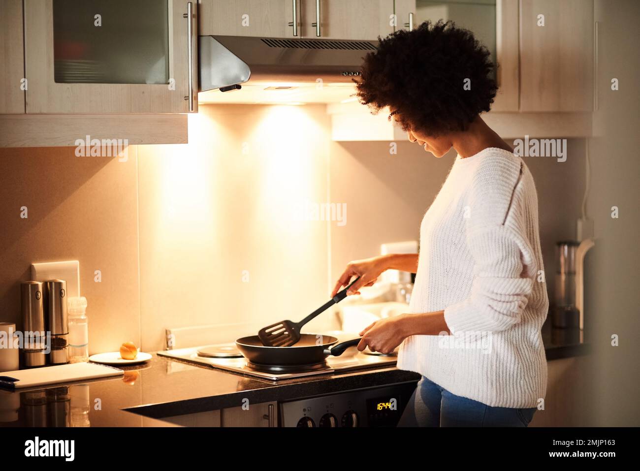 Nothing beats a classic fried egg for breakfast. a young woman cooking a fried egg at home. Stock Photo