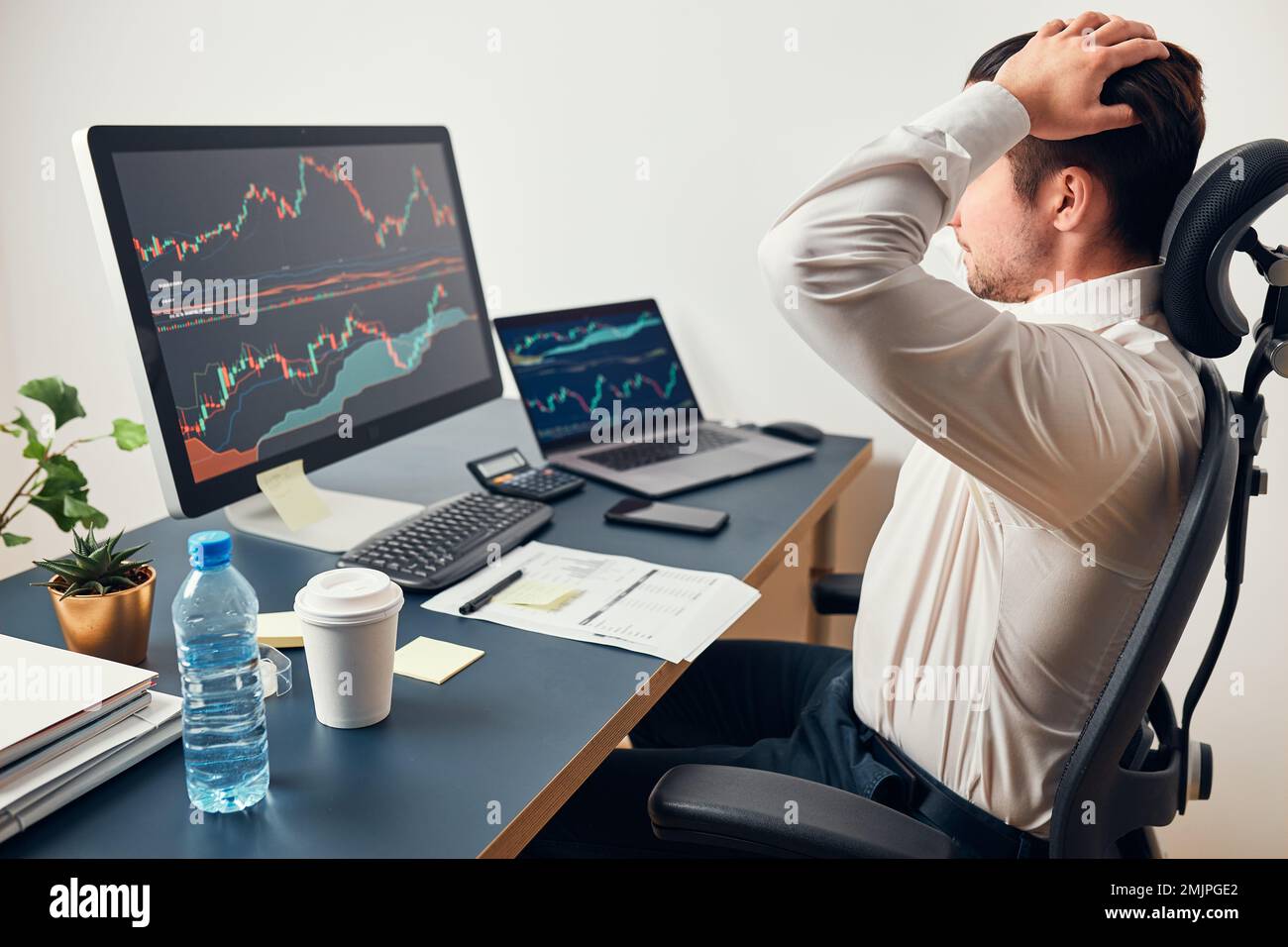 Worried businessman looking at charts stressed by news from stock market. Investor lost money online. Man analyses loss and profit. Businessman invest Stock Photo