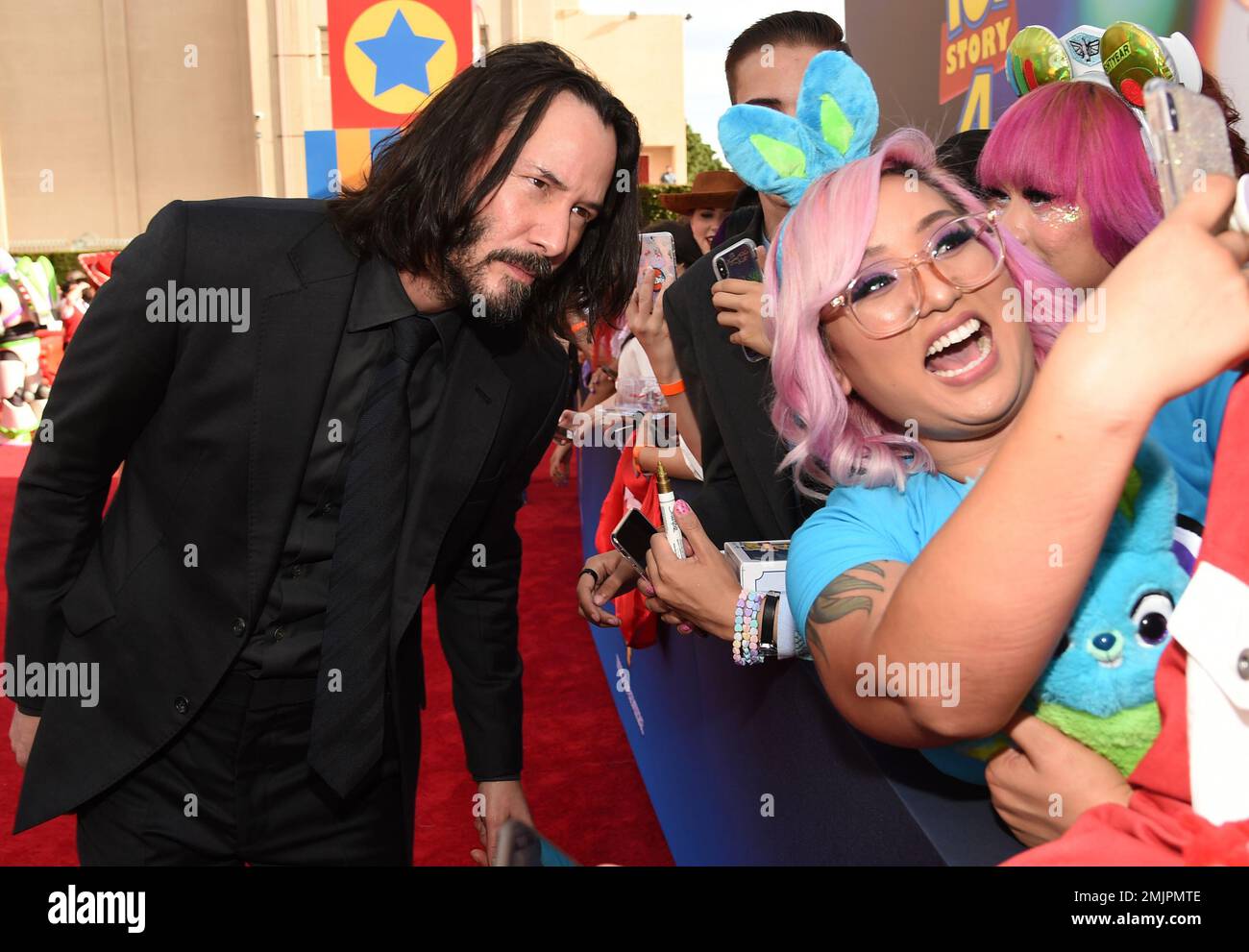 Keanu Reeves left takes a selfie with a fan as he arrives at the