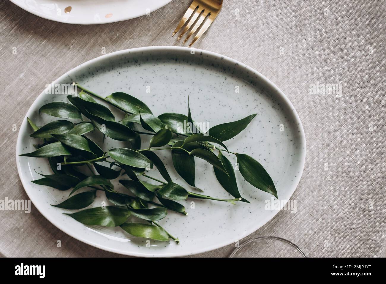 Rustic wedding table seting with vintage plates, green and white eucalyptus garland, gold utensils. Boho style. Table set for an event, party, date or Stock Photo