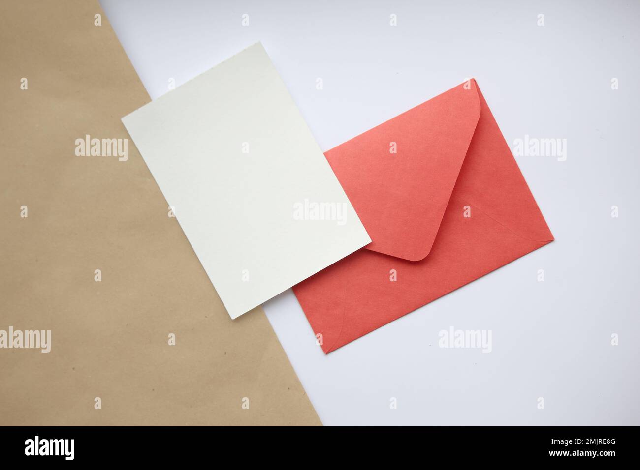 Postcard mockup vertical, on white and brown background red closed envelope and white sheet Stock Photo