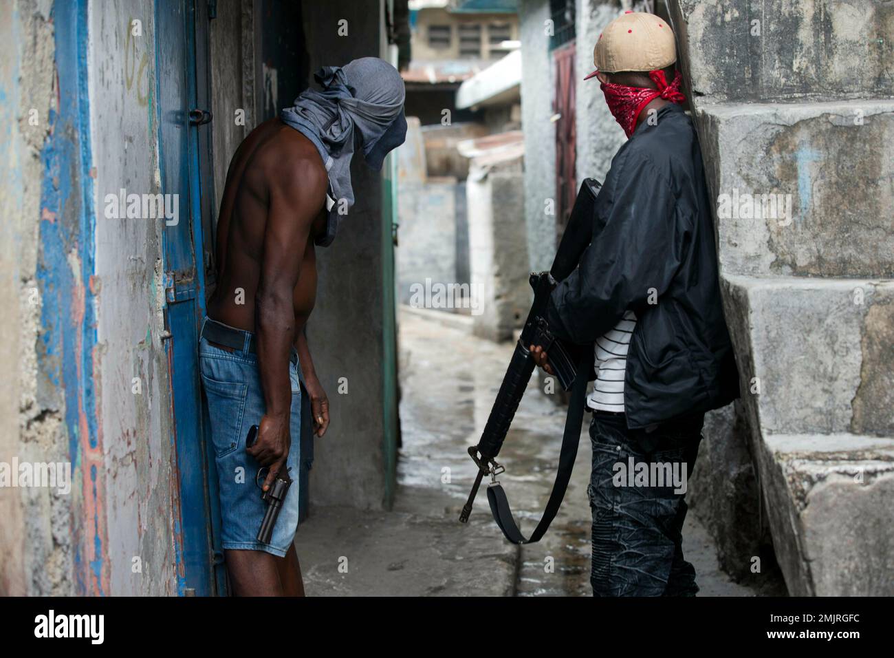 In this May 31, 2019, photo, gang members stand guard and hold guns six months after a massacre in the La Saline slum of Port-au-Prince, Haiti. “Gangs are multiplying because the government is weak,” said Paul Eronce Villard, Haiti’s general prosecutor, who estimates there are more than 50 gangs now operating in the country. “It’s a real challenge for police.” (AP Photo/Dieu Nalio Chery) Stock Photo