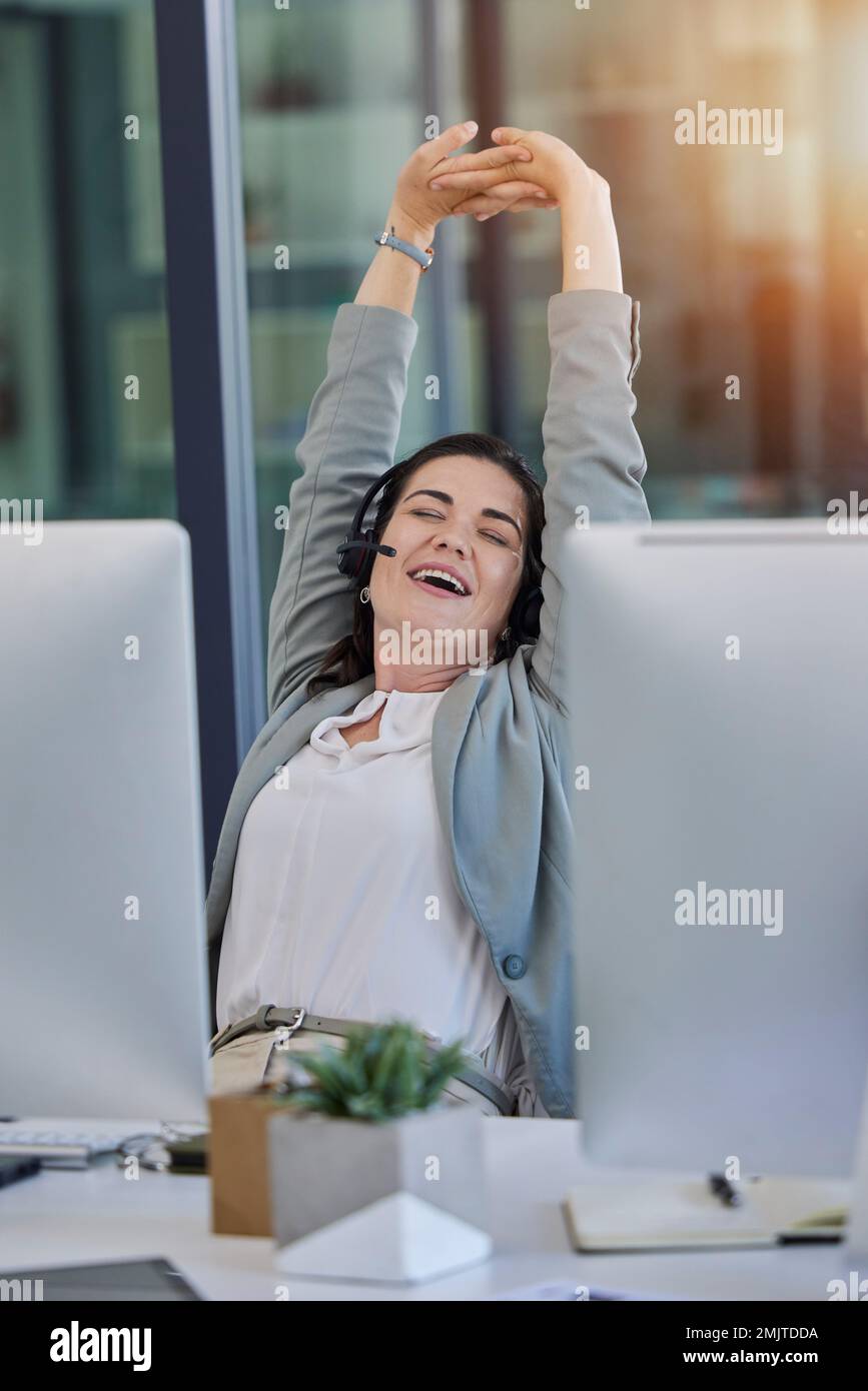 Call center, woman and tired with stretching in office by computer with smile, relax or customer service. Crm expert, telemarketing and consulting for Stock Photo