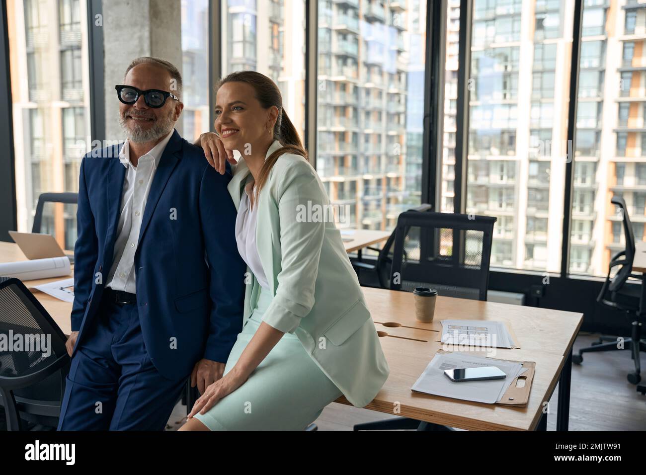 Two friendly coworkers in business attire posing gladly at office Stock Photo