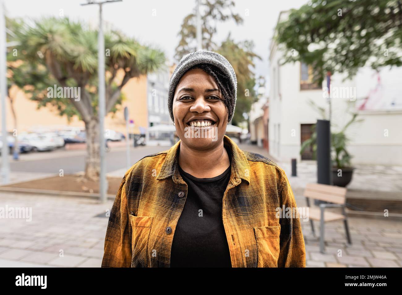 Happy African woman smiling in front of a camera in the city Stock Photo