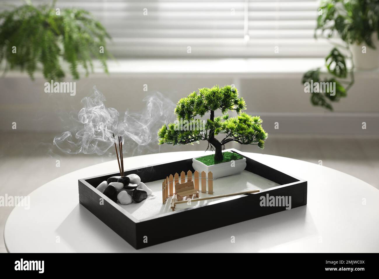 Beautiful miniature zen garden with incense sticks on table