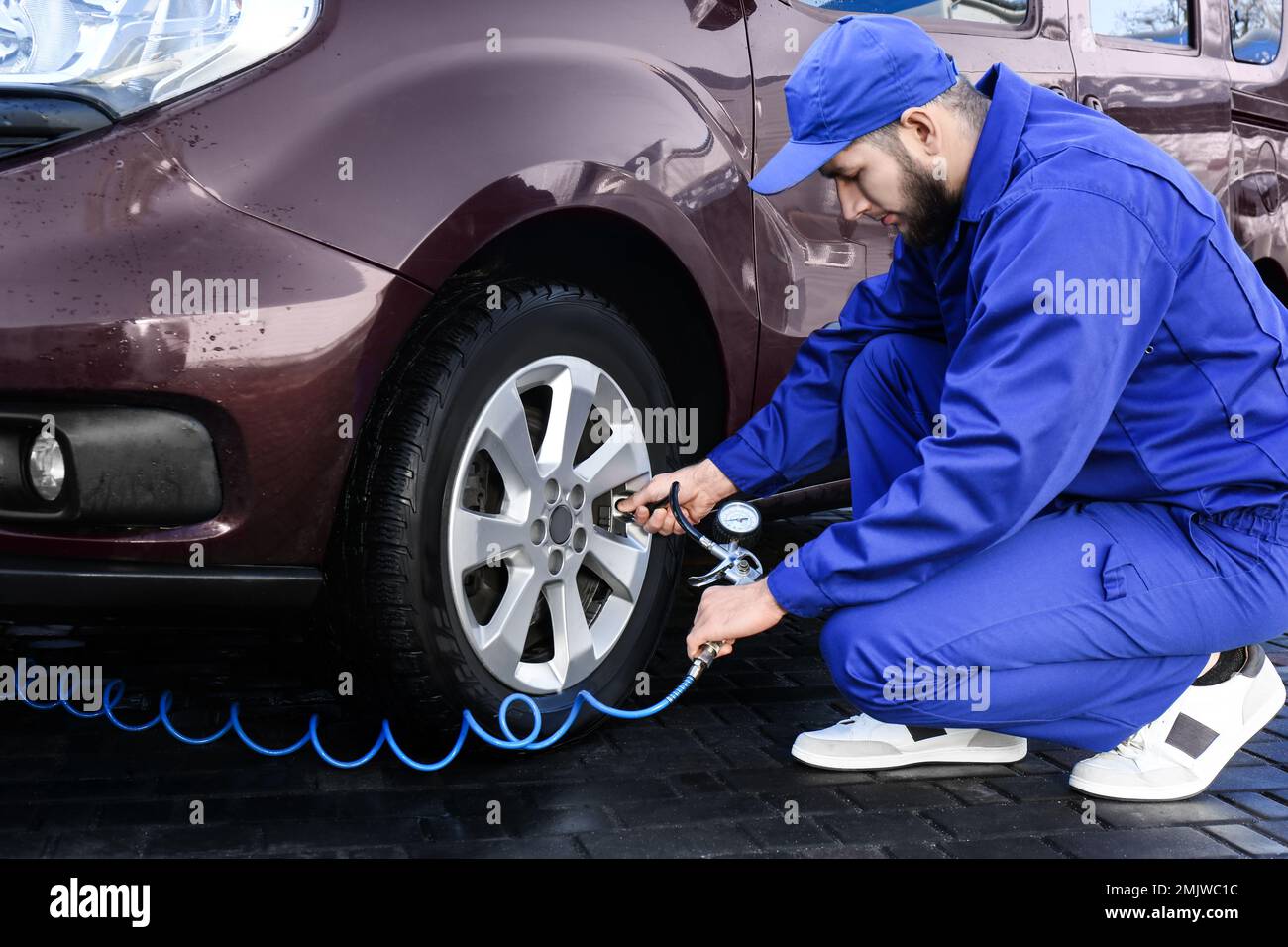 Mechanic checking tire air pressure at car service Stock Photo Alamy