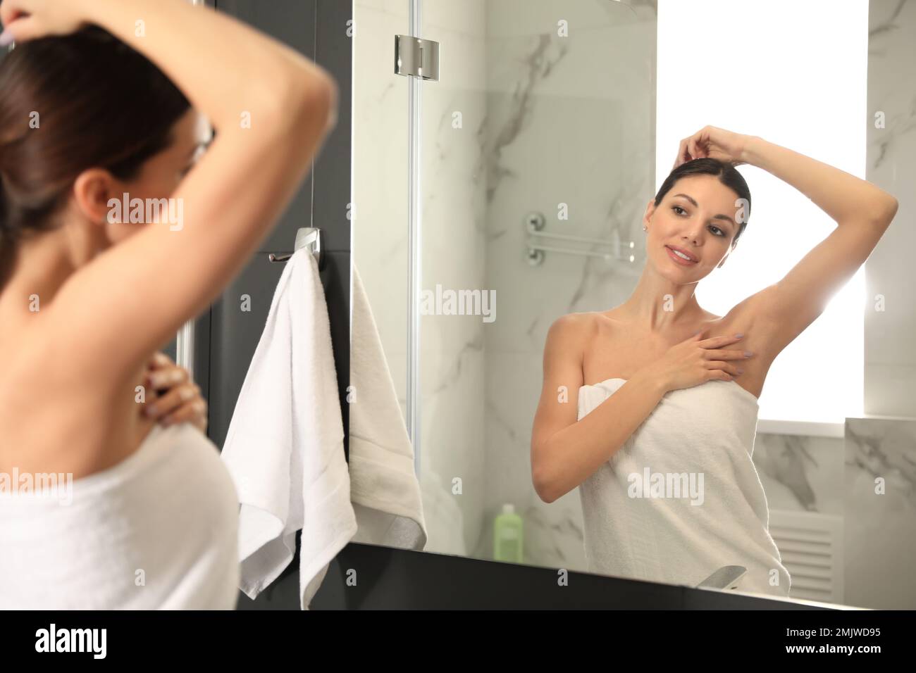 Young woman touching soft underarm skin after shaving in bathroom Stock
