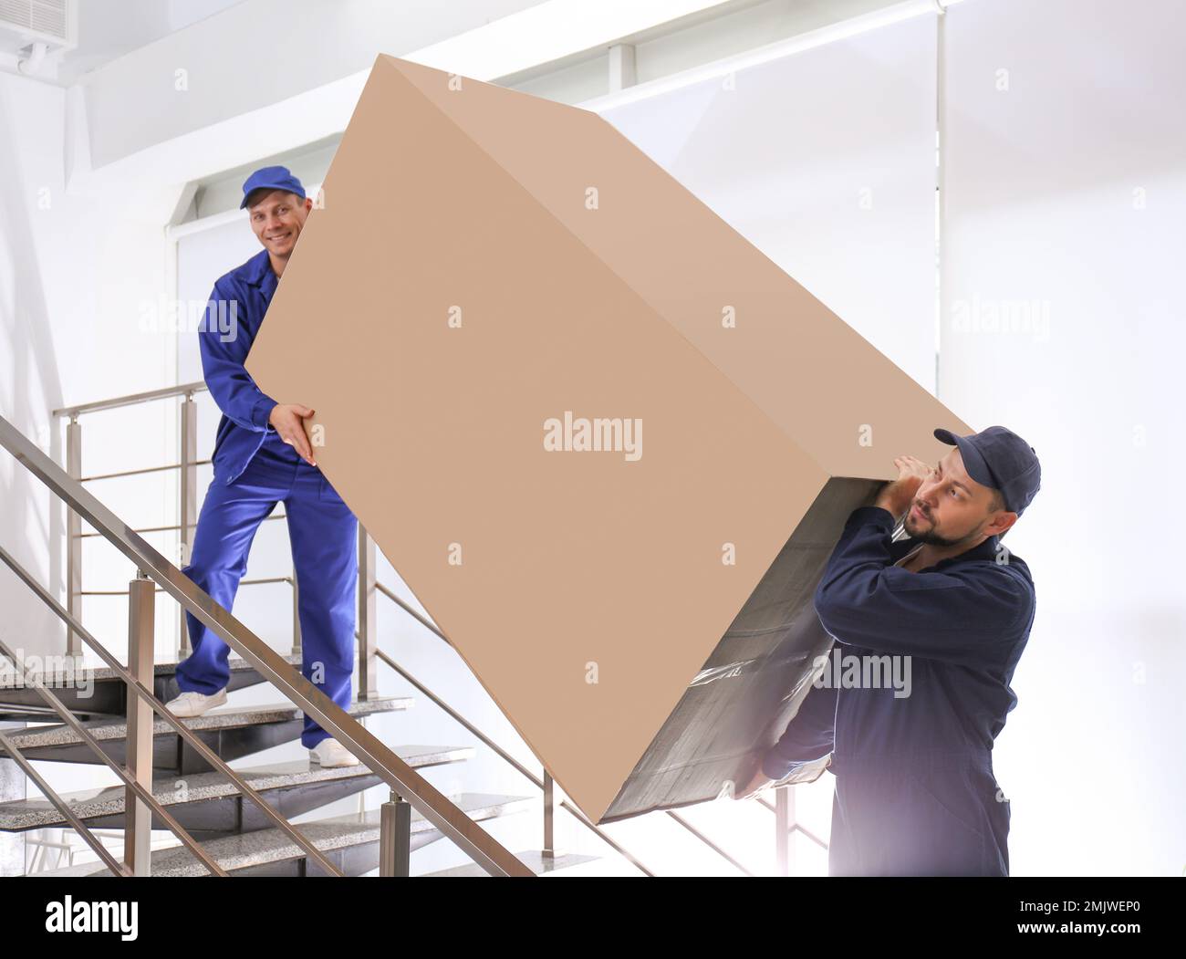 Professional workers carrying refrigerator on stairs indoors Stock